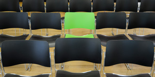 A green chair in the middle of black chairs
